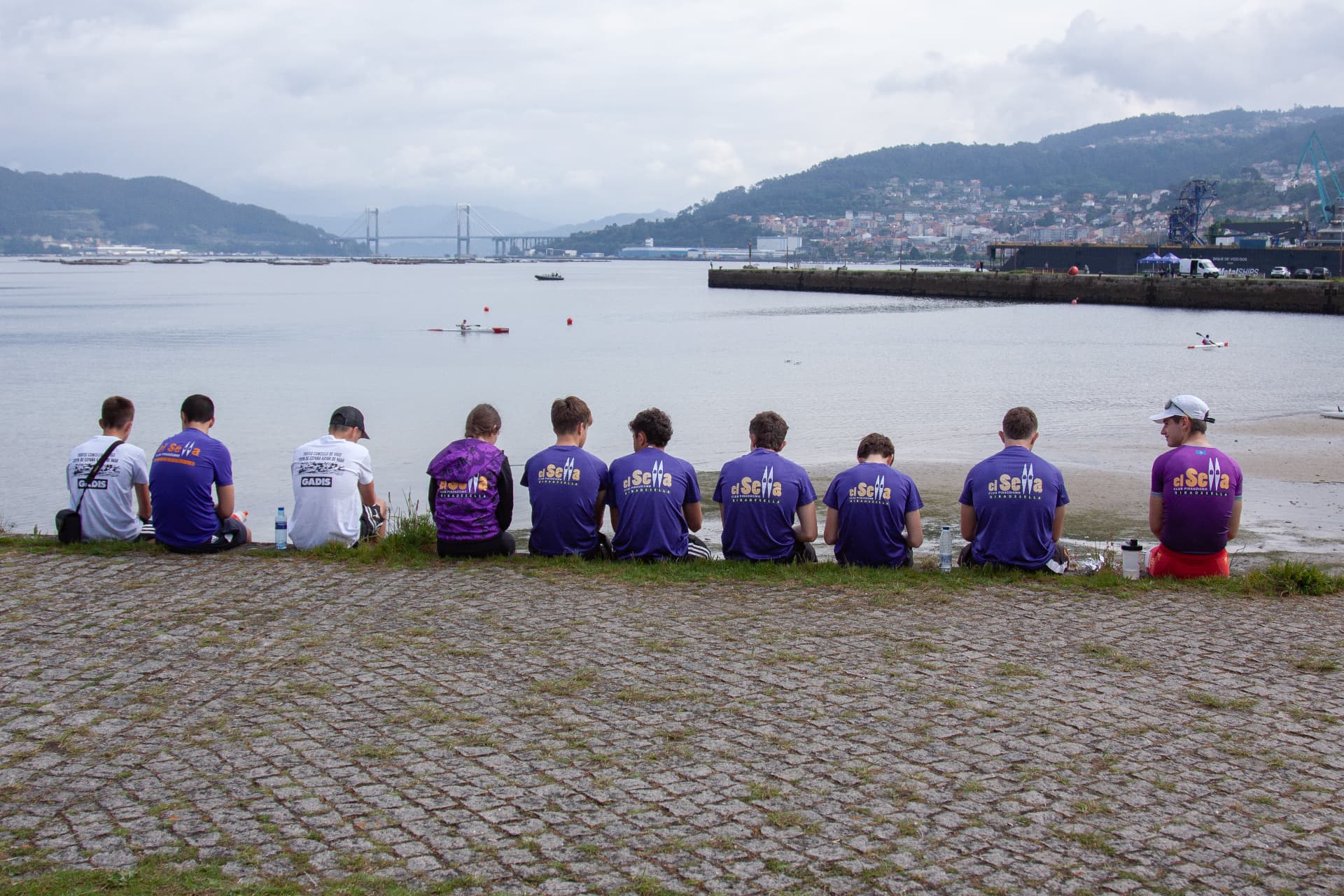 Equipo del Club Piragüismo El Sella sentado frente a la ría